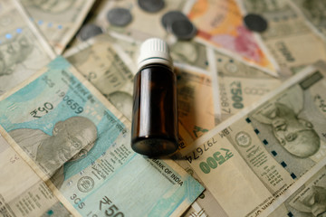 Empty Medicine bottle on Indian currency notes. Isolated focus. Medicine bill concept 