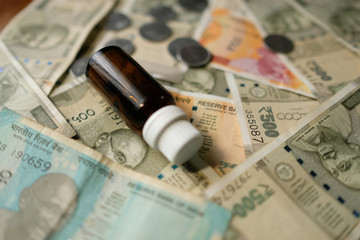 Empty Medicine bottle on Indian currency notes. Isolated focus. Medicine bill concept 