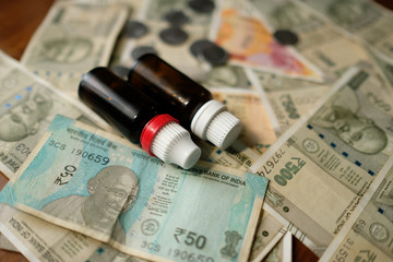 two Empty Medicine bottles on Indian currency notes. Isolated focus. Medicine bill concept 