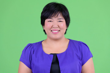 Face of happy young overweight Asian woman smiling