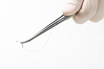 Doctor holding needle holder on white background. Suture thread. Nylon surgical thread.