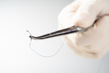 Doctor holding needle holder on white background. Suture thread. Nylon surgical thread.