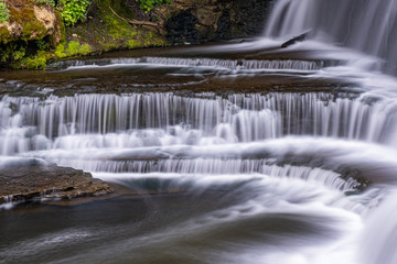 Obraz premium waterfall at belfountain conservation area Ontario Canada with trees, rocks, bridge, and long exposure