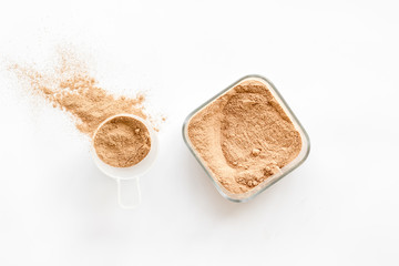 Sports nutrition with scoop and protein on white background top view