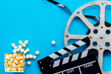 Go to the cinema with popcorn, film type and clapperboard on blue background top view mock-up