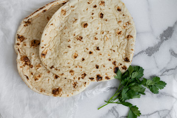 Indian tandoori baked naan on marble background, fresh herb cilantro and parsley, copy space