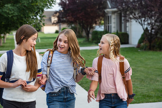 Group of young female friends and students talking together as they walk home school for the day