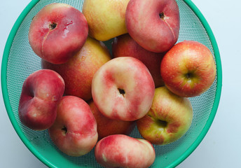 fresh peaches and apples in a fruit basket, top view, white background