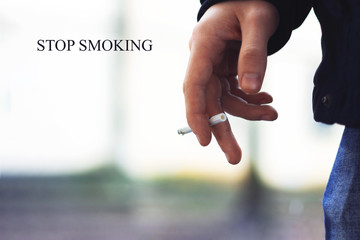 Young man's hand holding a cigarette with smoke
