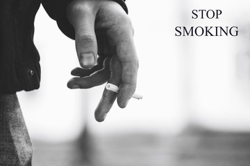 Young man's hand holding a cigarette with smoke