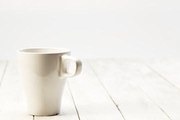 white empty cup on planked wooden table