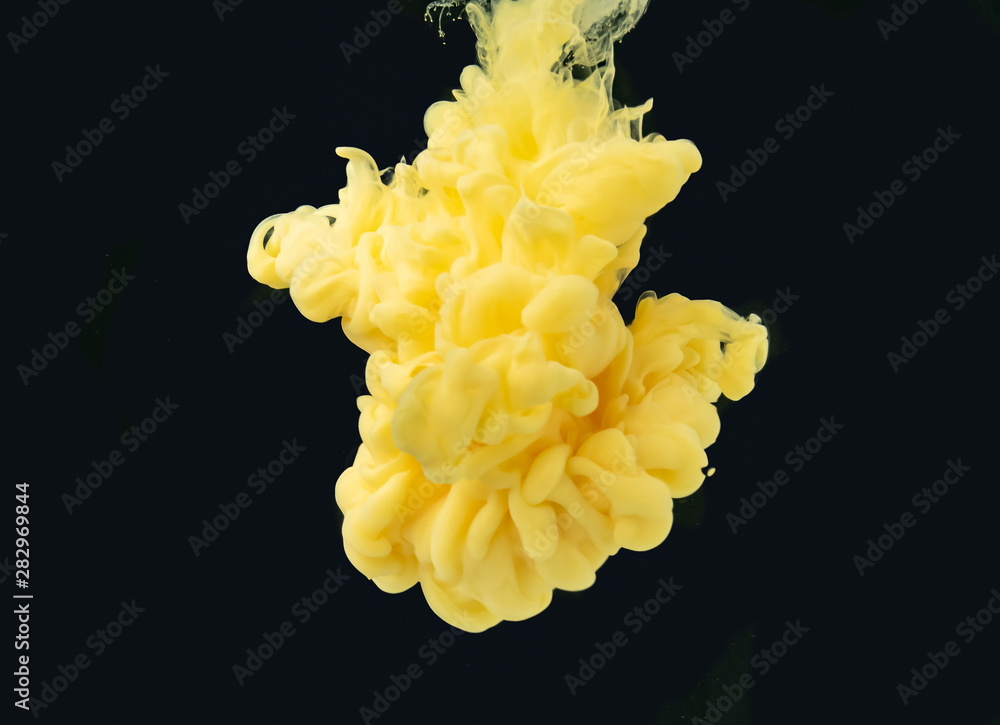 Poster yellow acrylic ink dissolving into water, isolated on black background, close up view. droplet of pa