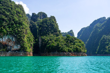 Green forest on limestone mountains in blue lake