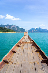 Wooden boat in turquoise water with limestone mountains and sky