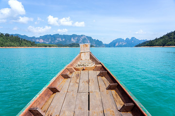 Wooden boat in turquoise water with limestone mountains background