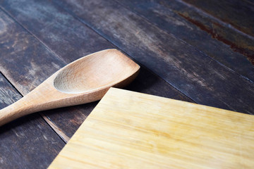 Wooden chopping board and spoon on dark wood table, vintage kitchen style