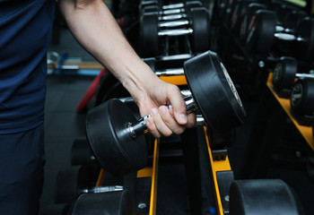 Fototapeta na wymiar A man are choosing dumbbells that are suitable for exercise in the gym,Selective focus