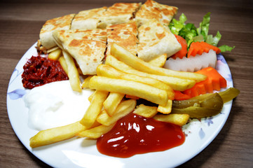 Shawarma chicken roll in a pita with fresh vegetables and cream sauce on wooden background. Selective focus