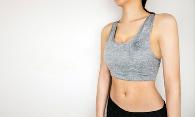 Fototapeta premium Fitness and Yoga Healthy Lifestyle Concept. Young Woman Wearing Gray Sport Bra with Muscular Body and Strong Six Pack in Gym. Sexy Female Posing in Sportswear (Sport Clothes) on Gray Background.