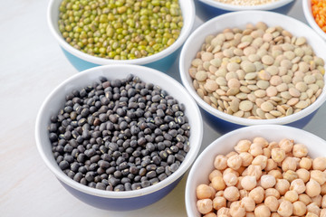 Different types of legumes in small pussies on a white background