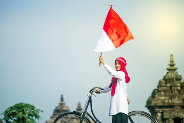 Asian Hijab flapper Indonesian flag in bicycle, Indonesia independence day