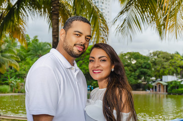 Fototapeta premium couple of young latin american men and women and happy in an outdoor portrait, together in a park, ju both romantically laughing and hugging