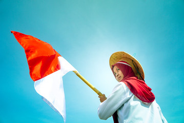 Asian Hijab flapper Indonesian flag with clear blue sky background, Indonesia independence day