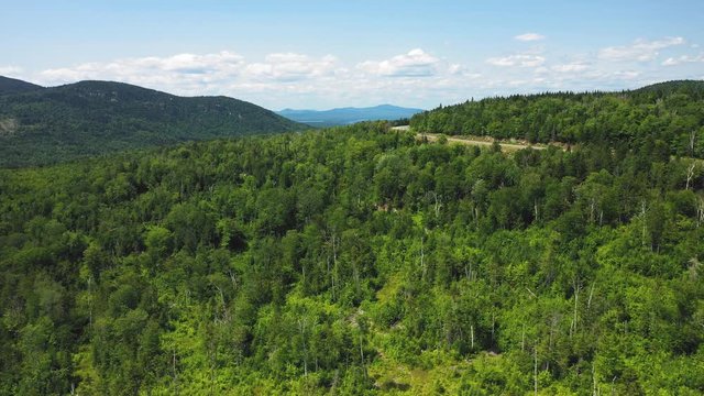 Wide Aerial shot over lush forestry approaching Rangeley Lake