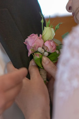 bride ties a boutonniere to the groom