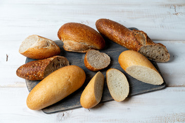 pieces different mini baguettes. Rye, wheat, multigrain bread on cutting board.