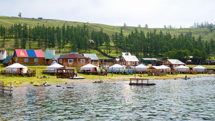 Tourist center in Turt (Khankh) village in Mongolia on the shore of Lake Hovsgol with a Mongolian flag on the roof . Yurts - a traditional home in Mongolia. 