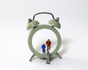 Miniature people walking out of the clock. The concept of old age and retirement.