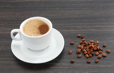 cup of coffee with beans on wooden table