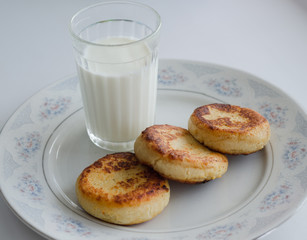 syrniki with cottage cheese and a glass of milk on a plate