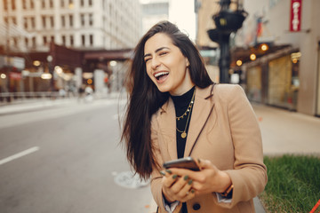 Beautiful girl in a city. Stylish brunette in a brown coat. Woman in a Chicago. Lady with a phone