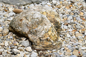 Large decorative stone and colorful worked stones on the ground.