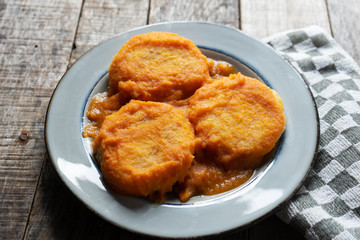 Mexican potato patties with red sauce on wooden background