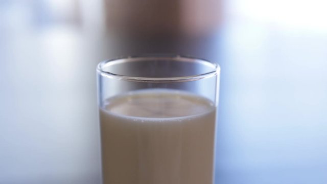 A glass of milk. the camera moves around the glass with milk. close-up. camera moves to the right. blurred background.