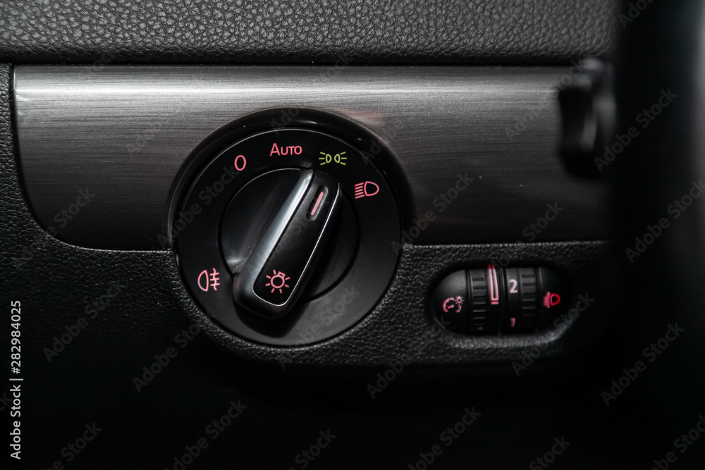 Poster close-up on the headlight switch control buttons, automatic adjust level dashboard. modern car inter