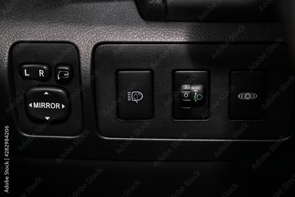 Poster close-up on the headlight, side mirror switch control buttons, automatic adjust level dashboard. mod
