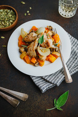 Seasonal autumn low calorie recipe from baked turkey medallions with pumpkin, onion, champignons and sage on a white plate.
