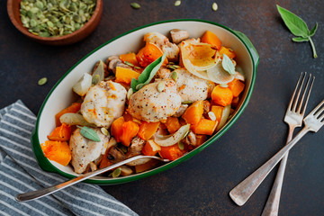 Top view on seasonal autumn low calorie recipe from baked turkey medallions with pumpkin, onion, champignons and sage in a ceramic dish.