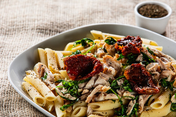 Pasta with chicken meat, sun-dried tomatoes and rucola