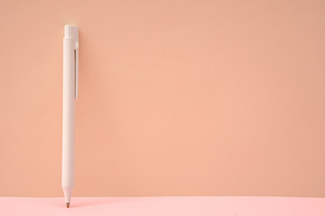 Pink color background and white ballpoint pen