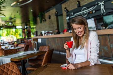 Portrait of woman smiling in coffee shop cafe vintage color tone. Smiling woman in a good mood with cup of coffee sitting in cafe. Bright sunny morning. Young woman sips coffee in coffee shop