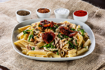 Pasta with chicken meat, sun-dried tomatoes and rucola