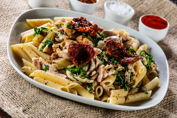 Pasta with chicken meat, sun-dried tomatoes and rucola