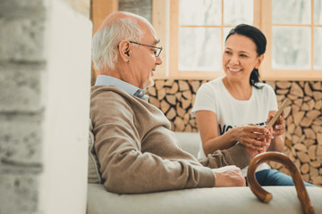 Smiling volunteer and old man spending time together