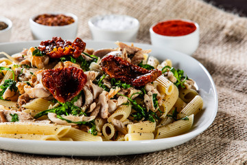Pasta with chicken meat, sun-dried tomatoes and rucola