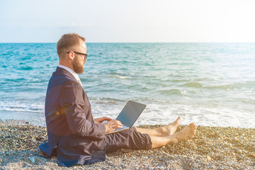 Businessman working with computer on the beach